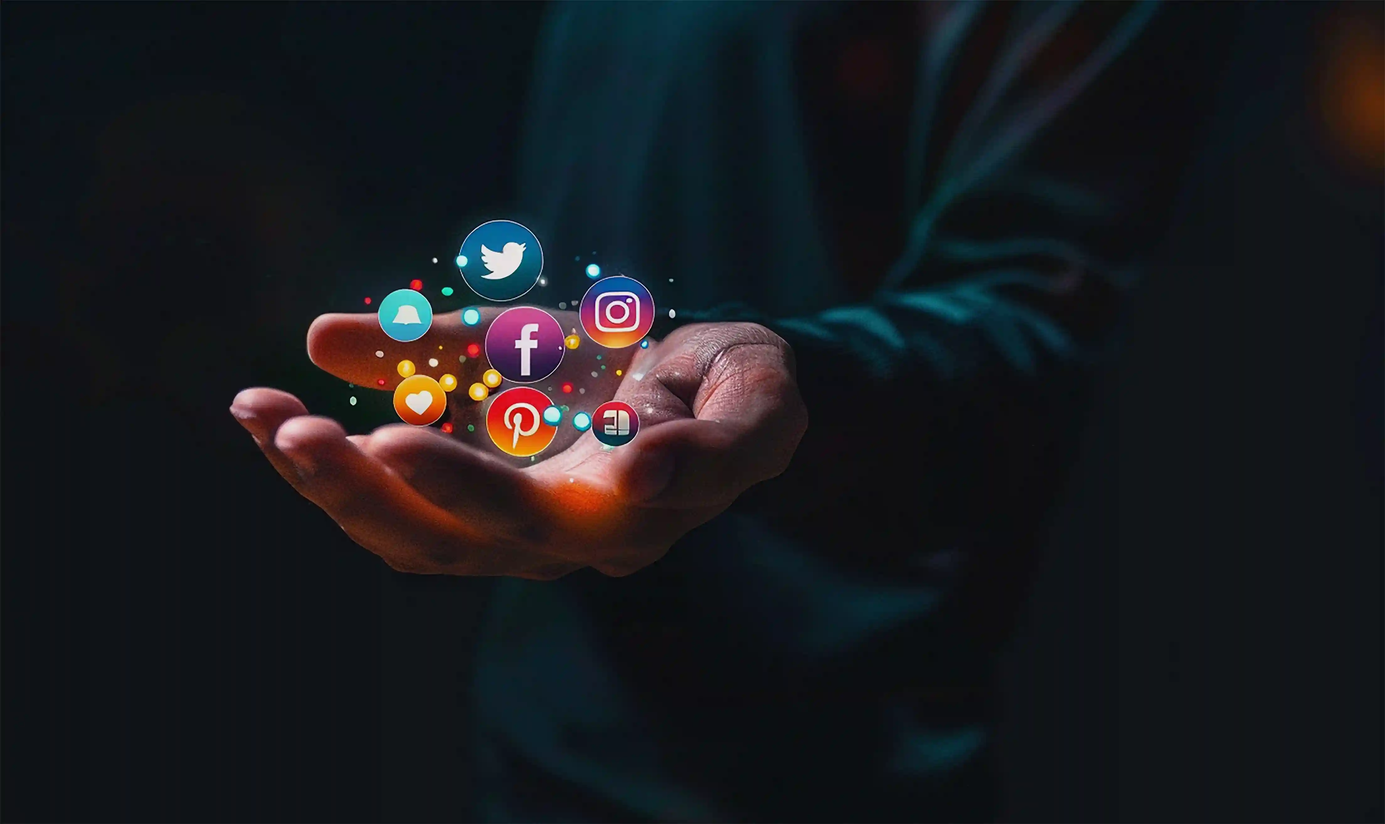 Hand holding floating social media icons with a dark background. Icons include Twitter, Facebook, Instagram, conveying a digital theme.