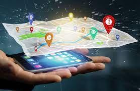 A hand holds a smartphone projecting a digital map with colorful location pins. The setting is futuristic with a tech-savvy vibe.